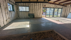 A commercial space undergoing construction with insulated walls and new concrete flooring by Rivera Services in Chandler, TX.