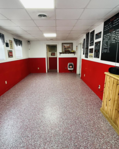 A completed commercial space renovation with red and white walls and a new speckled floor by A 2 Z Home Services - Fairmont WV.
