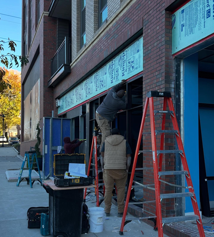 Workers installing a commercial storefront window frame for Capital Construction & Contracting LLC in Raleigh, NC