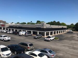 An aerial view of a commercial strip mall exterior, showcasing a completed renovation project by Spectrum Paint and Commercial Services, Inc. in Houston, TX.