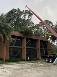 A large crane assisting with commercial tree removal and cleanup on a building roof by Green Leaf Tree Service in Broussard, LA.