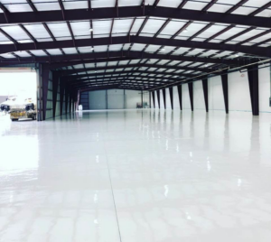 Wide view of a renovated commercial warehouse interior with new epoxy flooring by Catalyst Contracting in Cape Coral, FL.