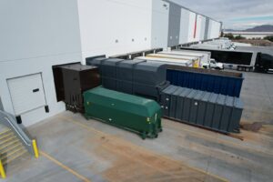 An aerial view of a commercial waste management system with multiple compactors and dumpsters at a loading dock, provided by Premier Service in North Las Vegas, NV.