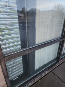 Close-up of a dirty commercial window frame needing cleaning or sealant repair by Duran Landscaping in Albuquerque, NM.