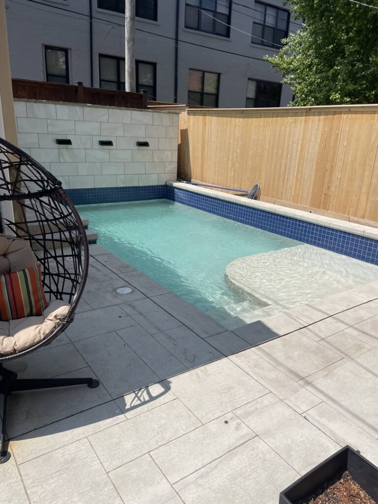 Compact backyard pool with a decorative tiled wall installed by Elevate Pools in O'Fallon, MO.