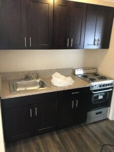 A compact kitchenette installation with dark cabinets and a small stove by BRM Construction in Miami, FL.