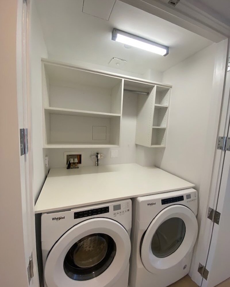 A compact laundry area with a countertop and custom shelving installed by Closet Creations Inc. in Sleepy Hollow, NY.