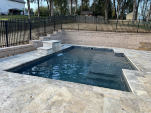 A compact pool design featuring a tiered waterfall and stone retaining wall by Southern Pool Solutions in Knoxville, TN.