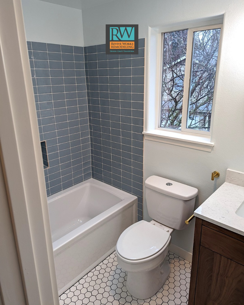 A complete bathroom remodel featuring new vanity, toilet, and tiled shower by Revive Works Remodeling in Portland, OR.