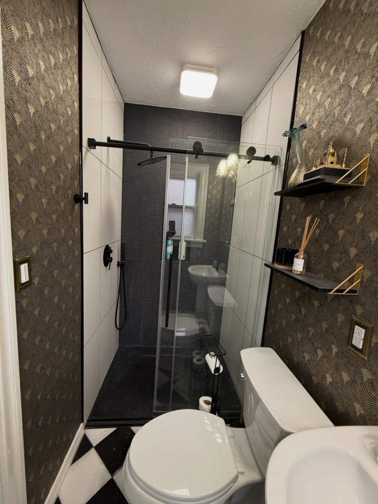 A complete bathroom remodel featuring a new shower, toilet, and wallpaper by Waking Up Construction in Oklahoma City, OK