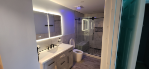 A complete bathroom renovation featuring a new vanity, illuminated mirror, and walk-in shower by Done Right Construction in Johnston, IA.