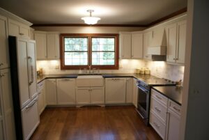 A complete kitchen remodel featuring white cabinets, dark countertops, and hardwood floors by Cincinnati Cabinet Refacing in Cincinnati, OH.