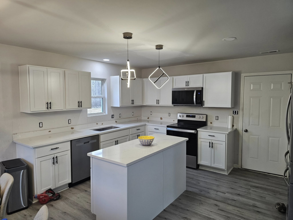 A complete kitchen renovation featuring new white cabinets, countertops, appliances, and modern lighting by All Trades Home Improvement in Hobart, IN.