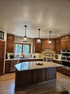 A beautifully completed kitchen renovation with new cabinets, granite island, and modern lighting by Boisen Remodeling LLC in Appleton, WI.