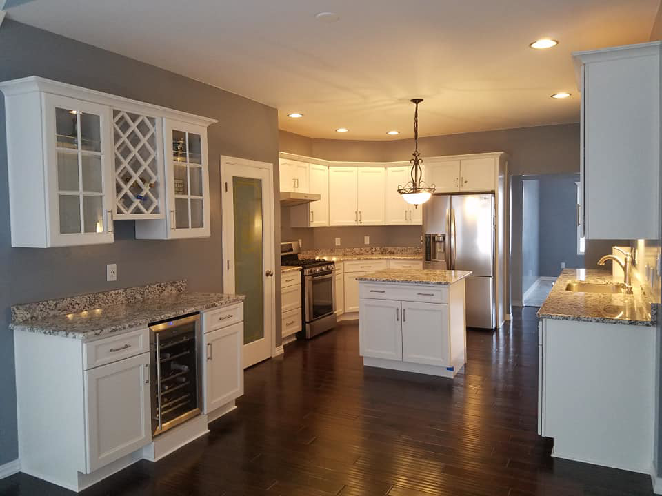 A complete kitchen renovation with white cabinets, an island, and a wine cooler by Land Bank Builders and Associates in Gary, IN