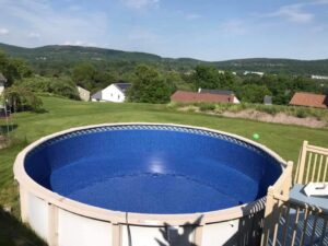 A beautifully completed above-ground pool installation in a backyard by Advanced Pools and Repair, LLC in Bristol, CT.