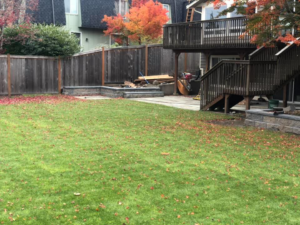 A completed backyard landscaping project with a new lawn, fence, and patio by M.C.Dirtworks in Caldwell, ID.