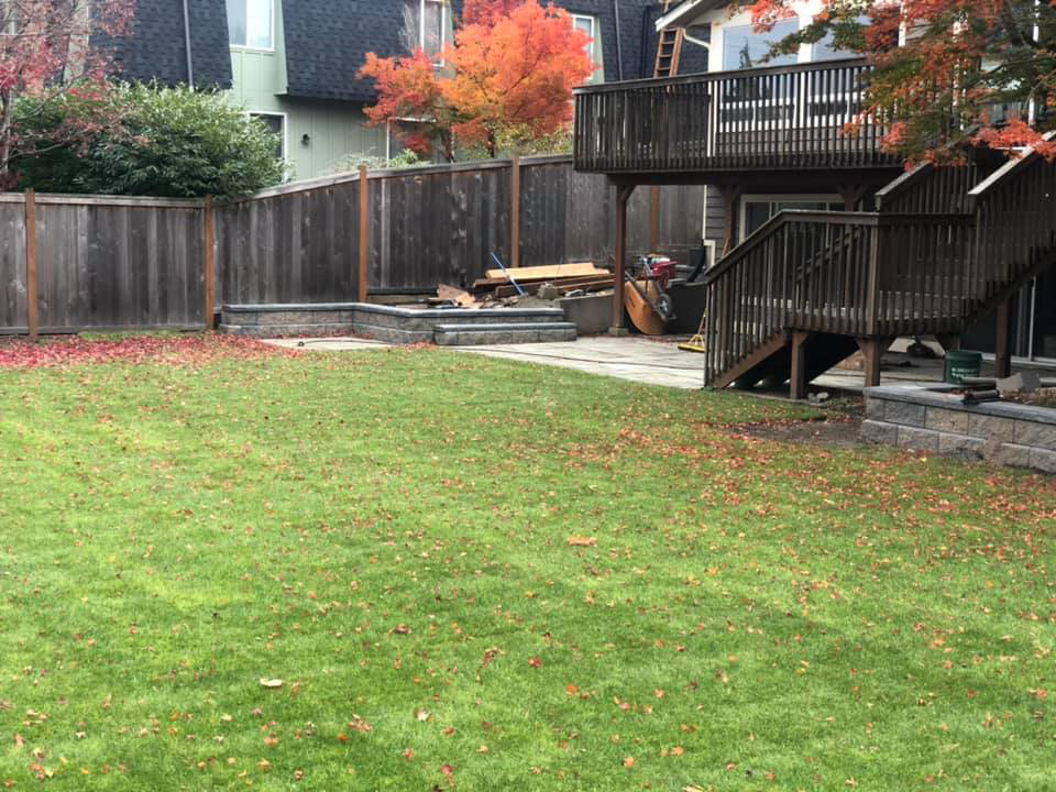 A completed backyard landscaping project with a new lawn, fence, and patio by M.C.Dirtworks in Caldwell, ID.