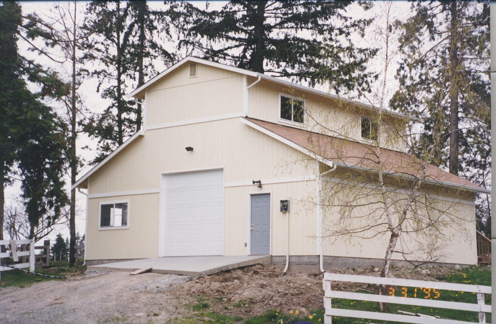 A large, newly built barn-style garage with light yellow siding by Garages Etc in Tacoma, WA