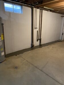 Newly waterproofed basement with concrete patch and white wall panels installed by Pioneer Basement Solutions in Canton, OH.