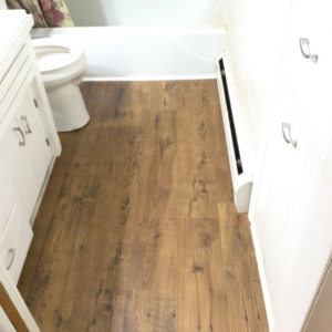 A newly installed wood-look laminate floor in a bathroom by Mr. Handyman of Charleston and Summerville in Summerville, SC.