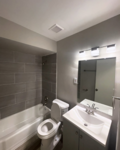 A newly remodeled bathroom with modern gray tiles, new vanity, and toilet by Make It Happen Homes STL in St. Louis, MO.