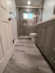 A beautifully completed bathroom remodel featuring a large vanity, toilet, and a walk-in shower with glass doors by Devco Construction LLC in West Valley City, UT.