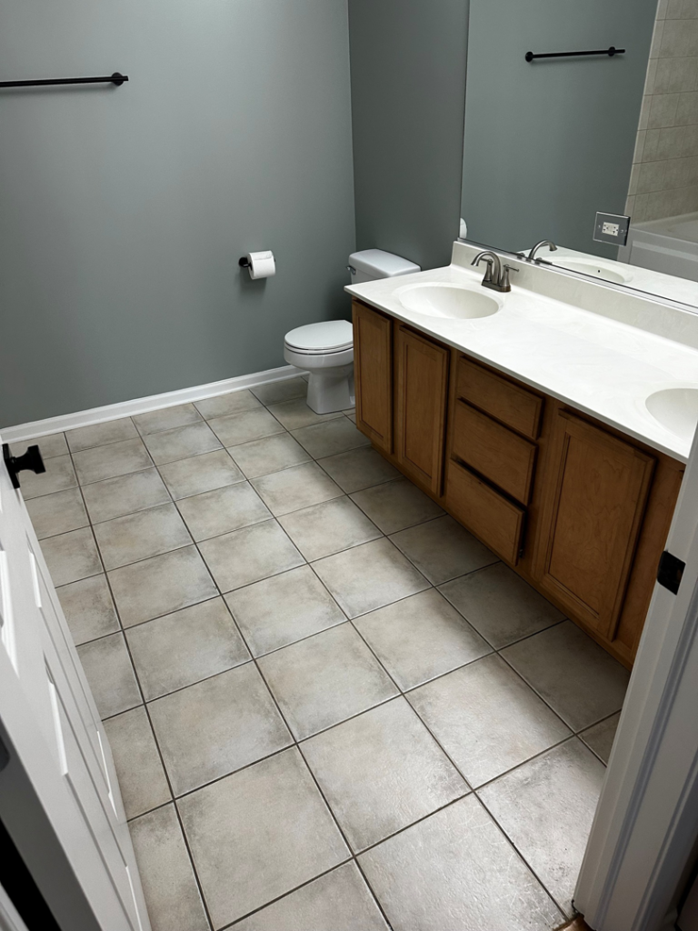 A completed bathroom renovation with a double sink vanity and tiled floor by All In Service Group, LLC in Chicago, IL.