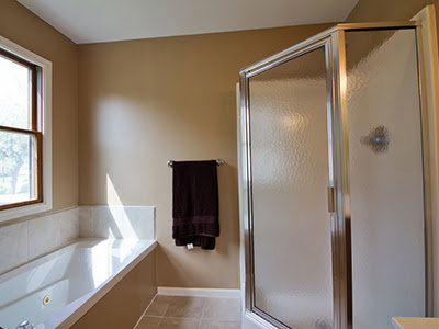 A modern, completed bathroom renovation featuring a glass shower and bathtub by Elk Building Services in Toledo, OH.