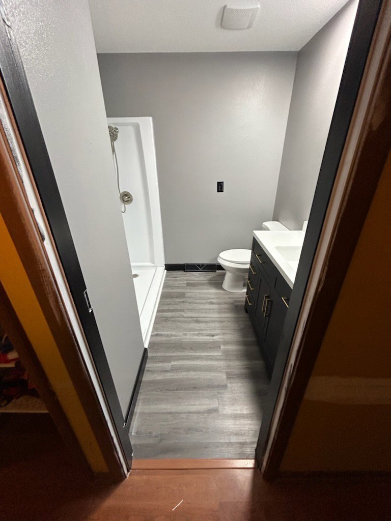 A newly completed bathroom renovation featuring new flooring, shower, and vanity by Justin-case Repairs in Ankeny, IA.