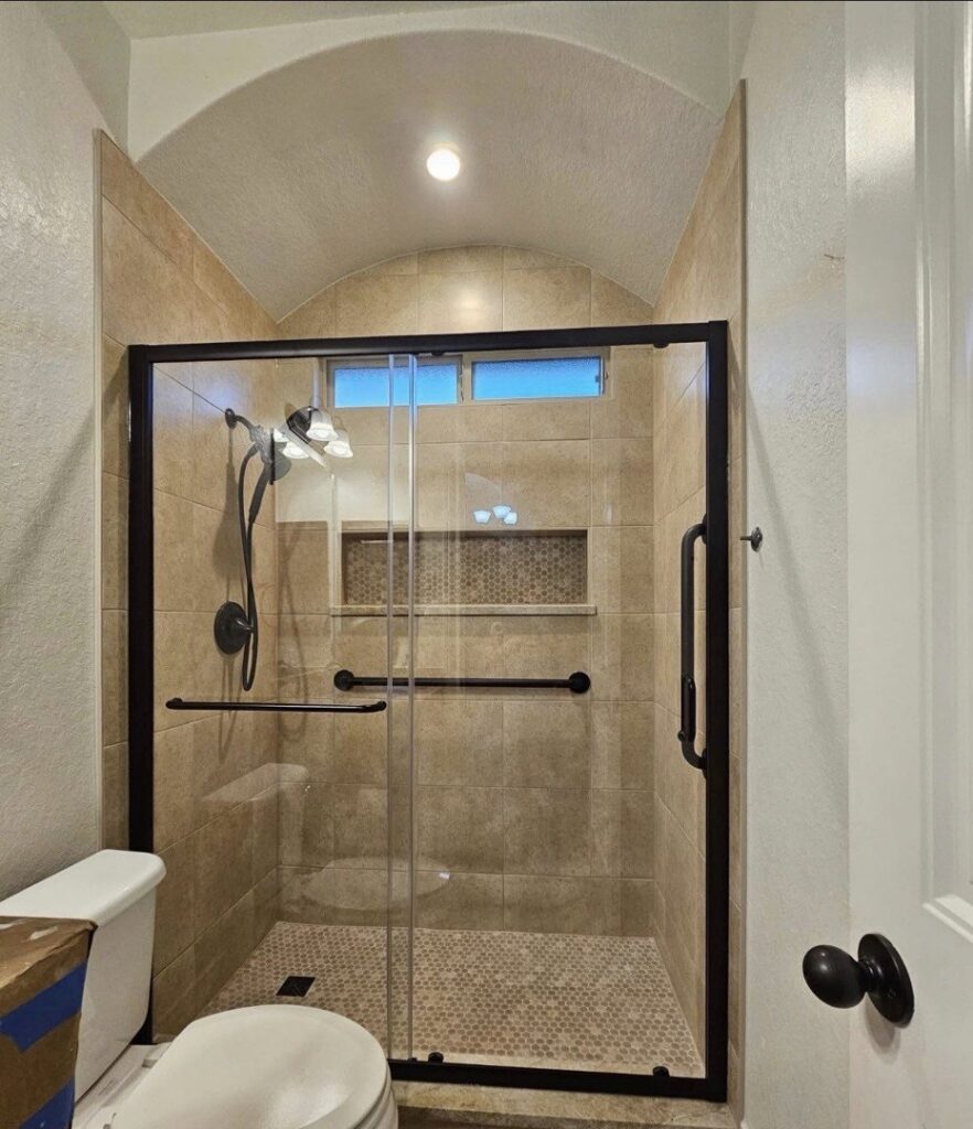 A completed bathroom featuring a tiled shower with a glass door and modern fixtures by TEXAN Home Improvements LLC in San Antonio, TX.