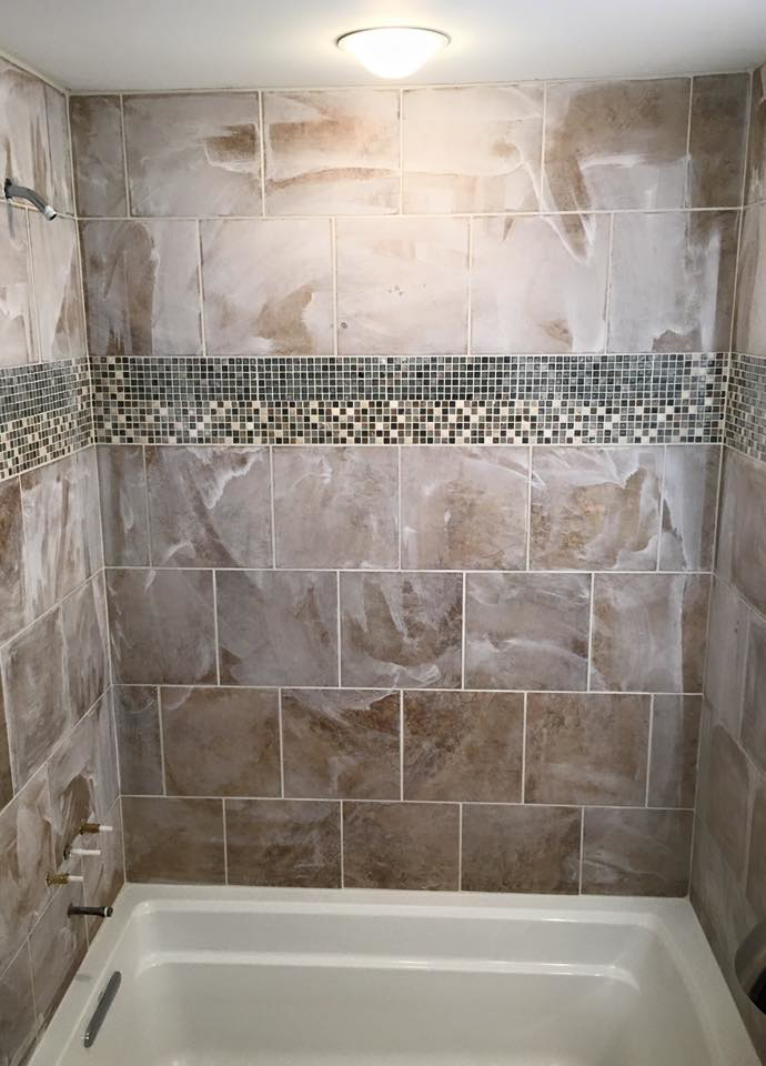 A completed bathroom shower tiling project with brown tiles and a decorative mosaic band by I'll Fix It in Shawnee, KS.