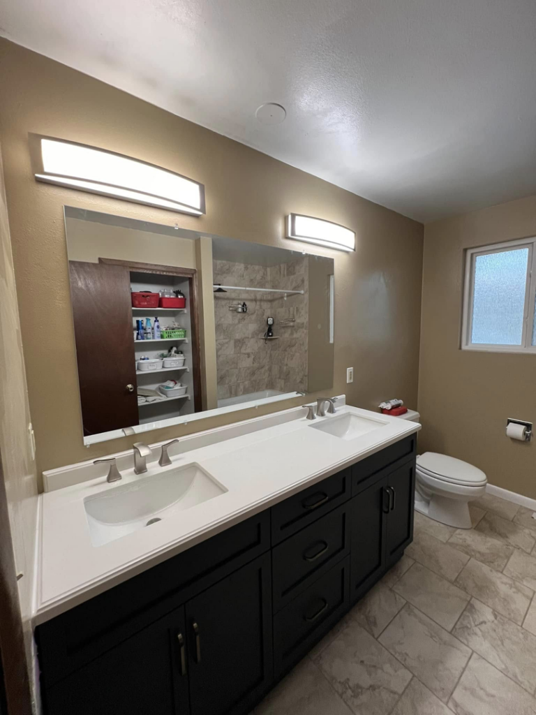 A newly completed bathroom featuring a double vanity, large mirror, and modern light fixtures by JP Handyman Wyo in Sheridan, WY