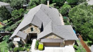 Aerial view of a house with a newly completed brown shingle roof by PaRu Construction LLC in San Antonio, TX
