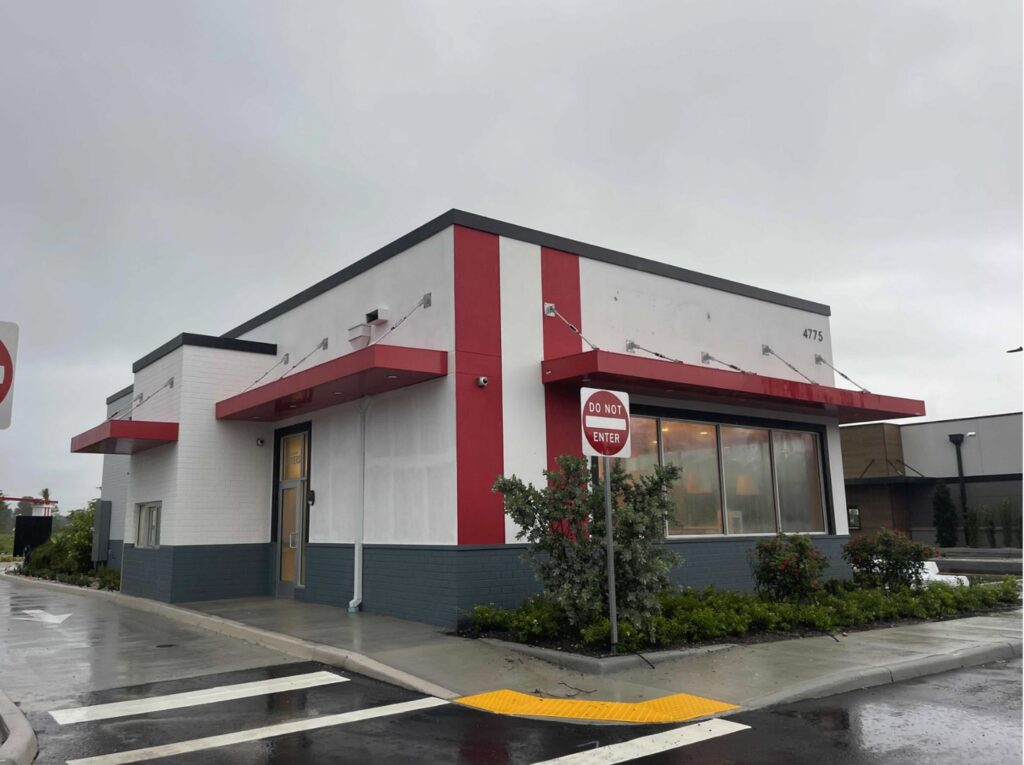 A newly completed commercial building exterior with red and white accents by M&J Florida Enterprise Llc in Orlando, FL.