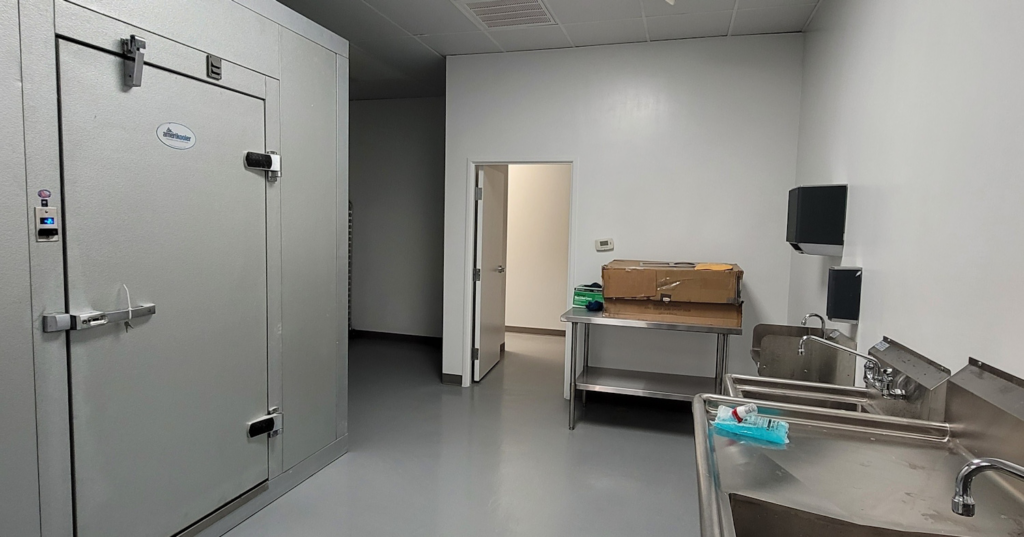 Completed commercial kitchen and food prep area with walk-in cooler by Visionary Construction Group in Plano, TX