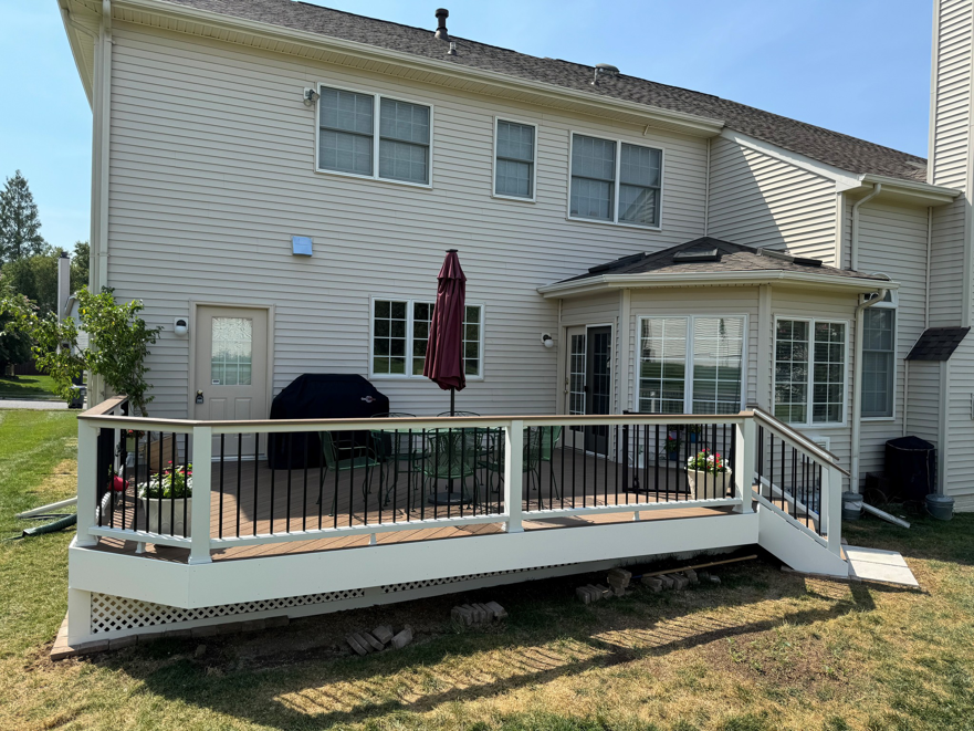 A wide view of a newly installed composite deck with railings and stairs attached to a house by Sundecks, Inc. in Manassas, VA.