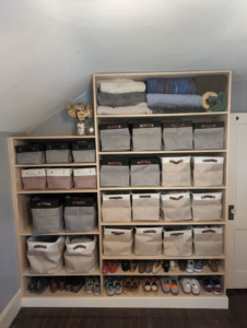 A completed custom wooden shelving unit, organized with bins and shoes, by Friendly Neighborhood Handyman in Uxbridge, MA.