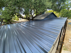 A completed dark grey metal roof installation on a building extension by J&J ultimate roofing llc in Austin, TX