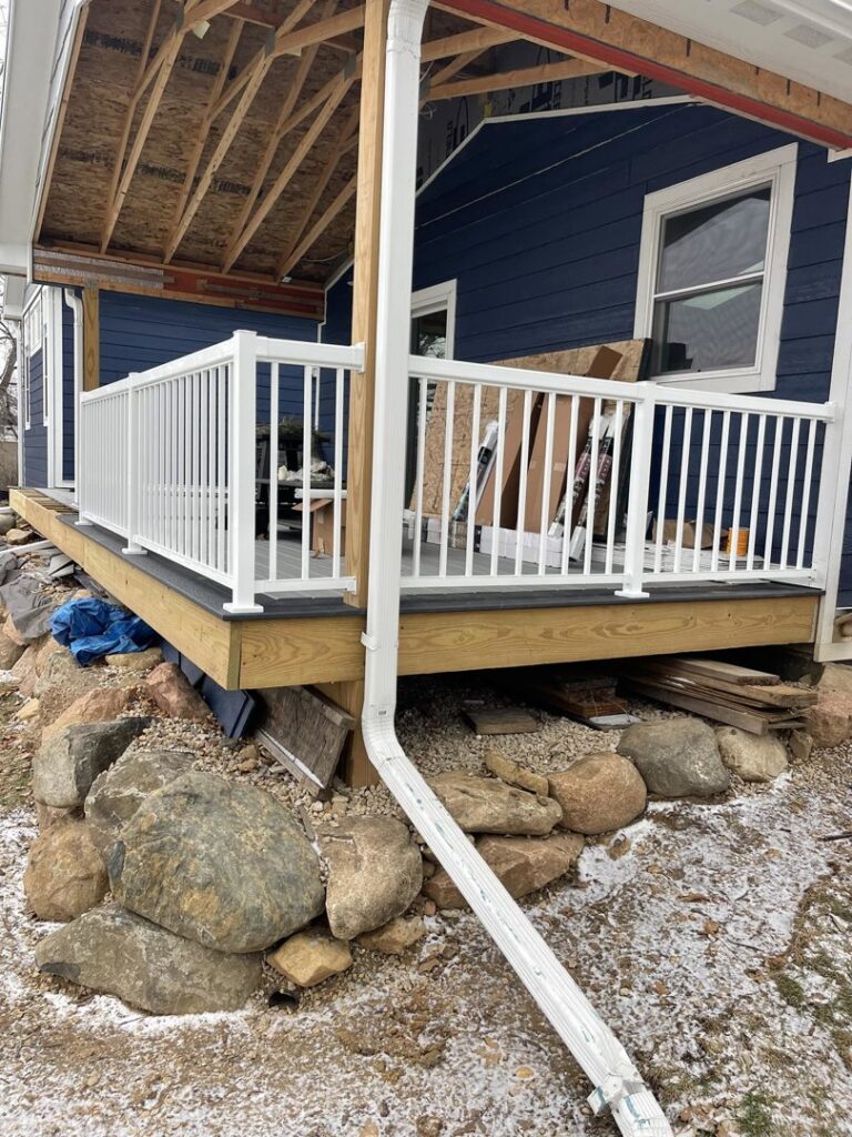 A newly completed deck with white railings and a downspout by S-Squared Construction in Madison, WI.