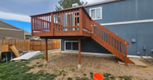 A newly stained wooden deck and stairs on the back of a house, completed by All Hung Up LLC in Littleton, CO.