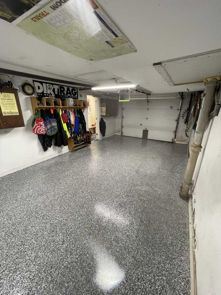 A completed speckled epoxy garage floor looking towards the open door by Epoxy Evolution in Albany, NY.