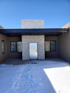 A completed exterior renovation of a home with new stone veneer and a patio covered in snow by AV Handyman Services in Rio Rancho, NM.