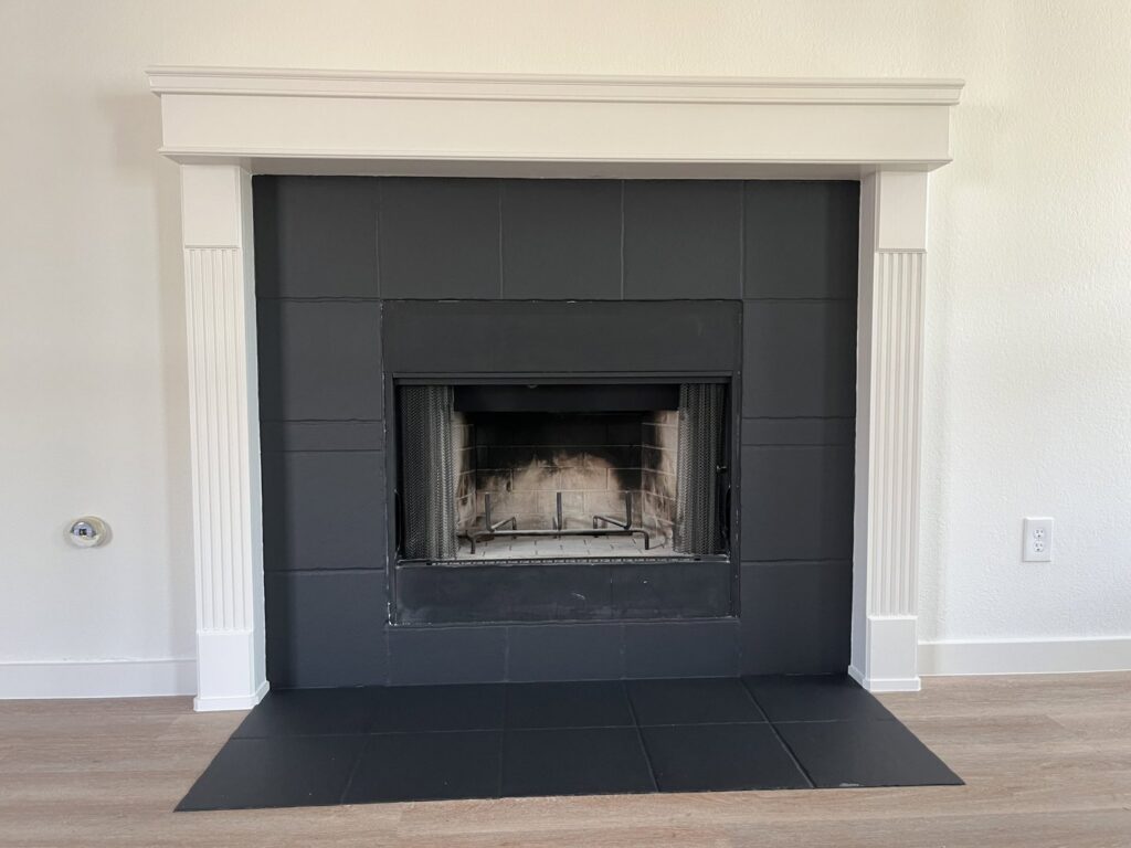 A newly renovated fireplace with black tile and white mantel by San Marcos Drywall and Paint in Austin, TX