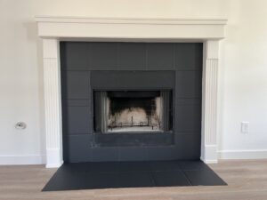 A newly renovated fireplace with black tile and white mantel by San Marcos Drywall and Paint in Austin, TX
