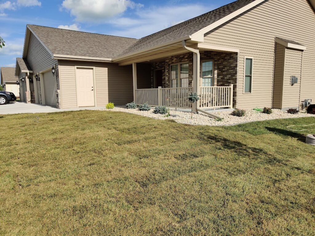 A completed front yard landscaping project featuring gravel and various plants by Wildflower Landscapers LLC in Larsen, WI