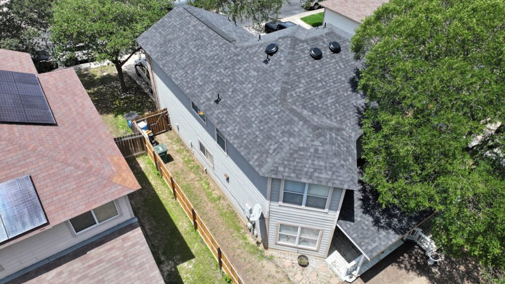 Aerial view of a residential house with a newly completed gray shingle roof by PaRu Construction LLC in San Antonio, TX