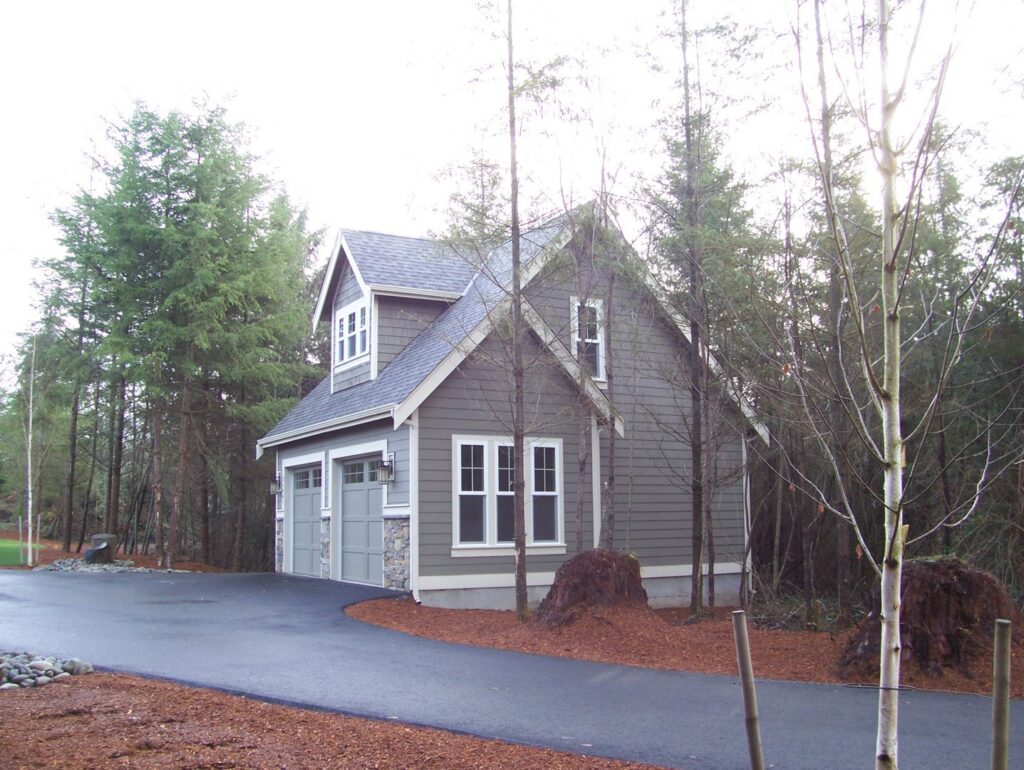 A newly built garage with gray siding and stone accents by Garages Etc in Tacoma, WA