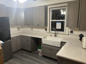Completed kitchen renovation featuring new grey cabinets, white quartz countertops, and a farmhouse sink by Byrd's Contracting, LLC in Bristol, CT.