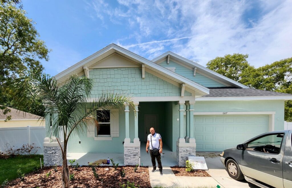 A completed home project with a man standing in front, built by Coastal Pointe Homes, a general contractor in Tampa, FL.
